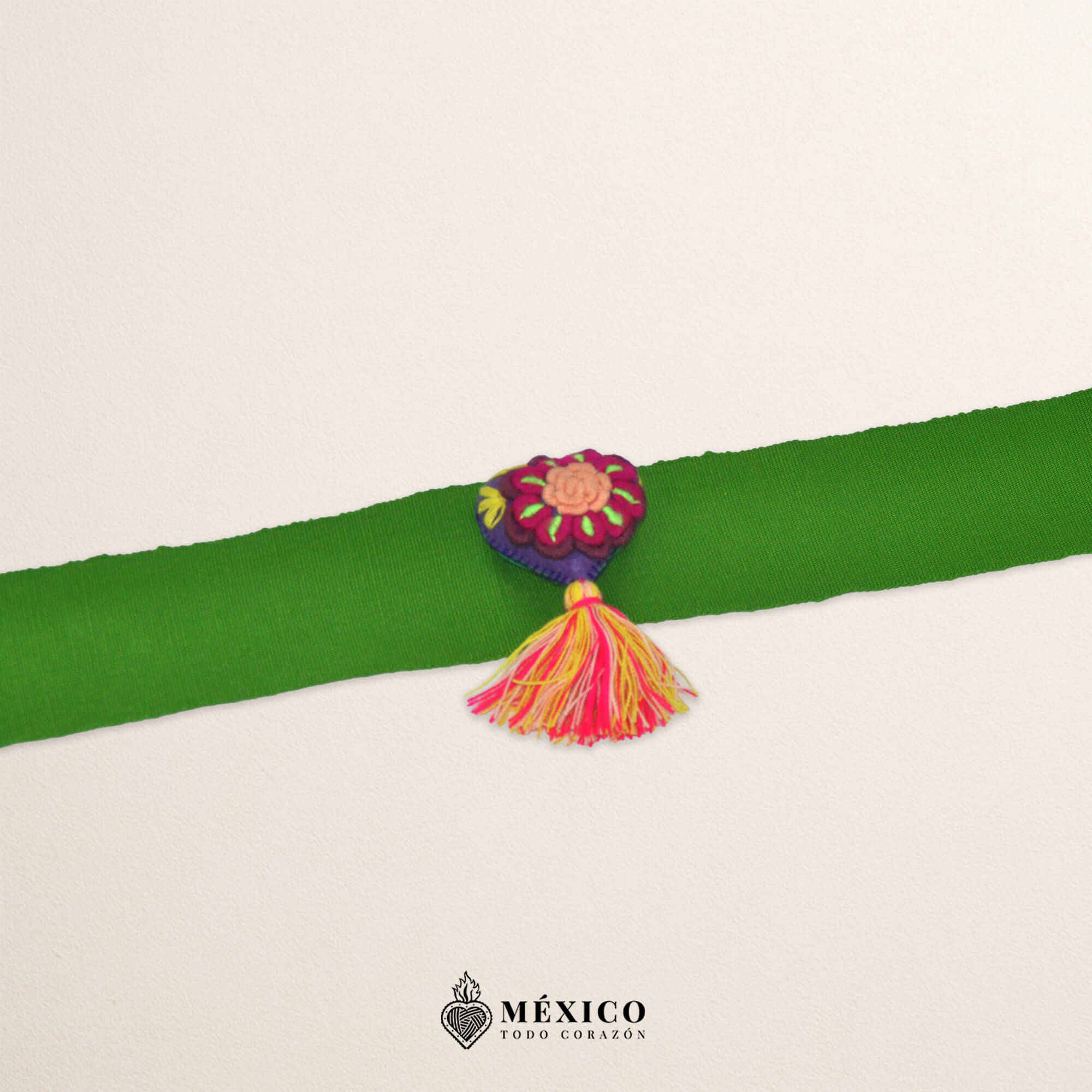 Green artisan Mexican waist belt featuring a floral heart embellishment in multicolor felt